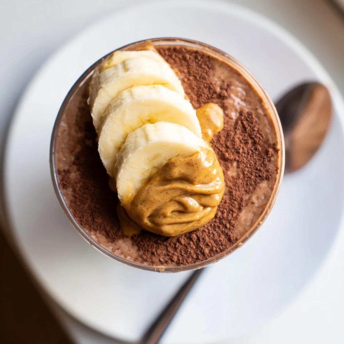 Chocolate Peanut Butter Smoothie in a tall glass, garnished with drizzles of peanut butter and sweet banana slices.