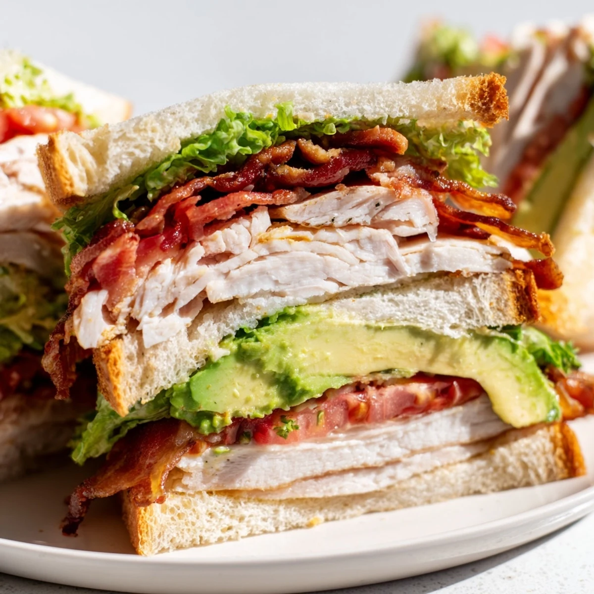 A triple-decker Turkey Club Sandwich with Turkey Bacon and Avocado sits on a wooden board, ready to be enjoyed for lunch.