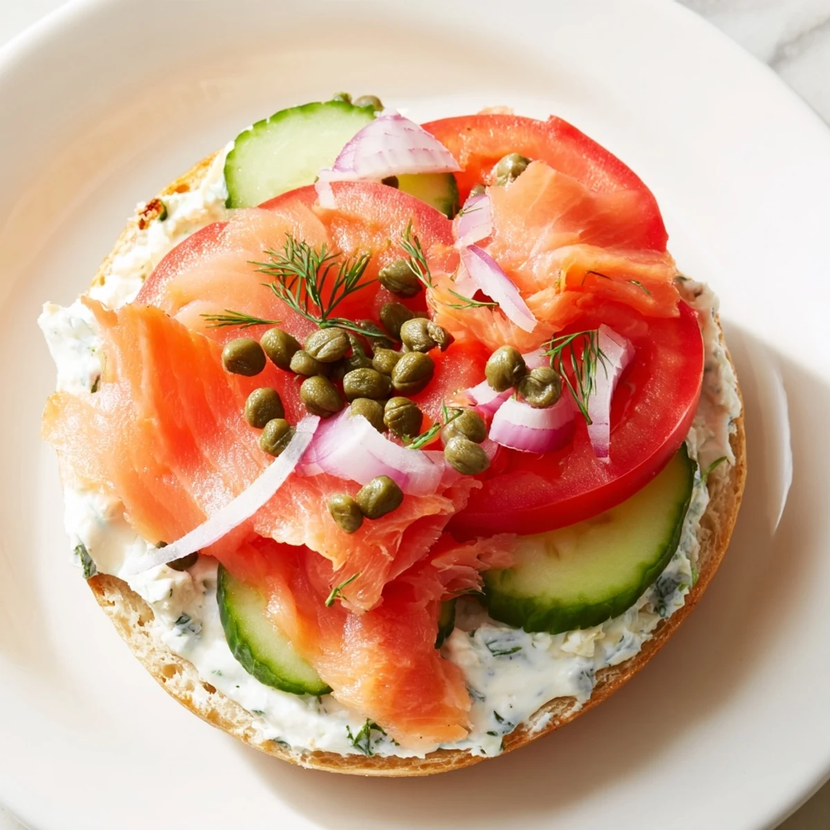 A close-up of the Baked Salmon Brunch Bagel shows flaky salmon, herbed cream cheese, and fresh dill on an everything bagel.